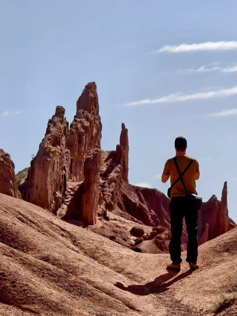 Hiker standing before towering rock spires in Skazka (Fairytale) Canyon